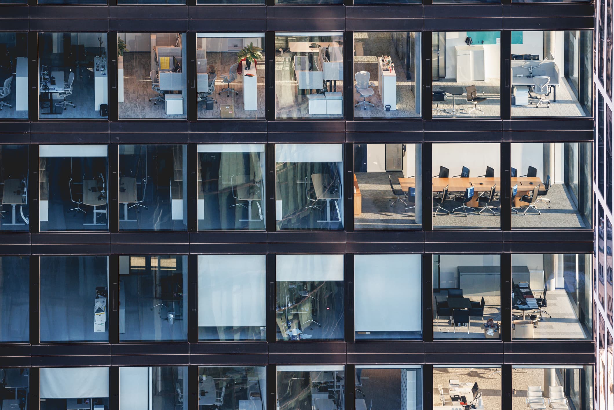 Offices behind corporate building windows, ceiling to floor glass facade in steel frame